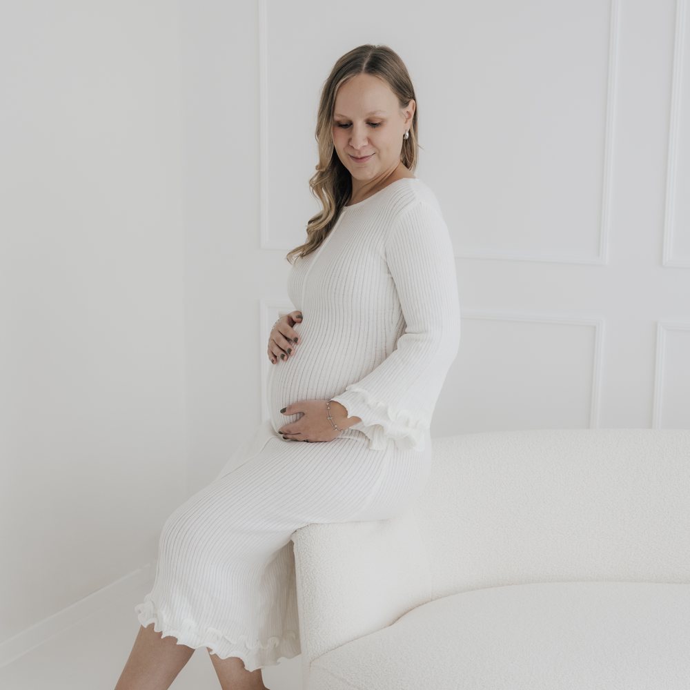 Schwangere im weißen Kleid im Studio