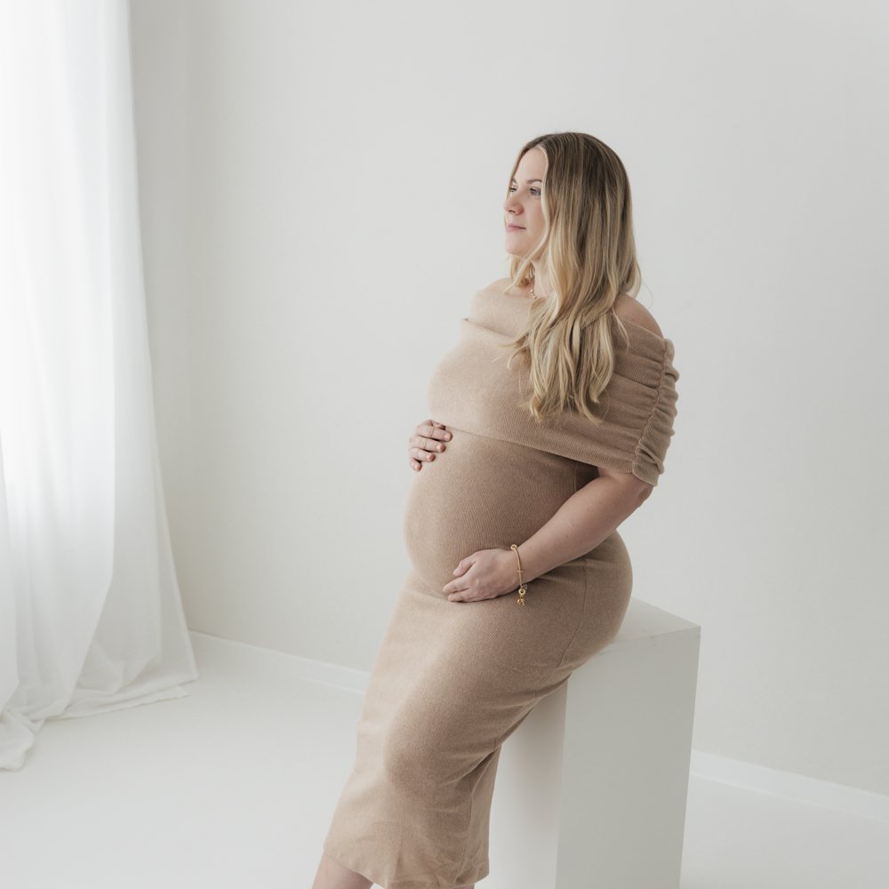 Schwangere im Kleid am Fenster