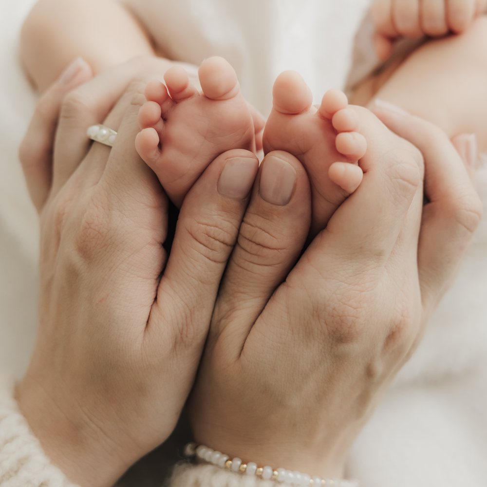 Babyfüße in den Händen der Eltern