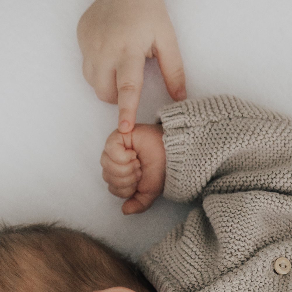 Neugeborenes hält den Finger der Eltern