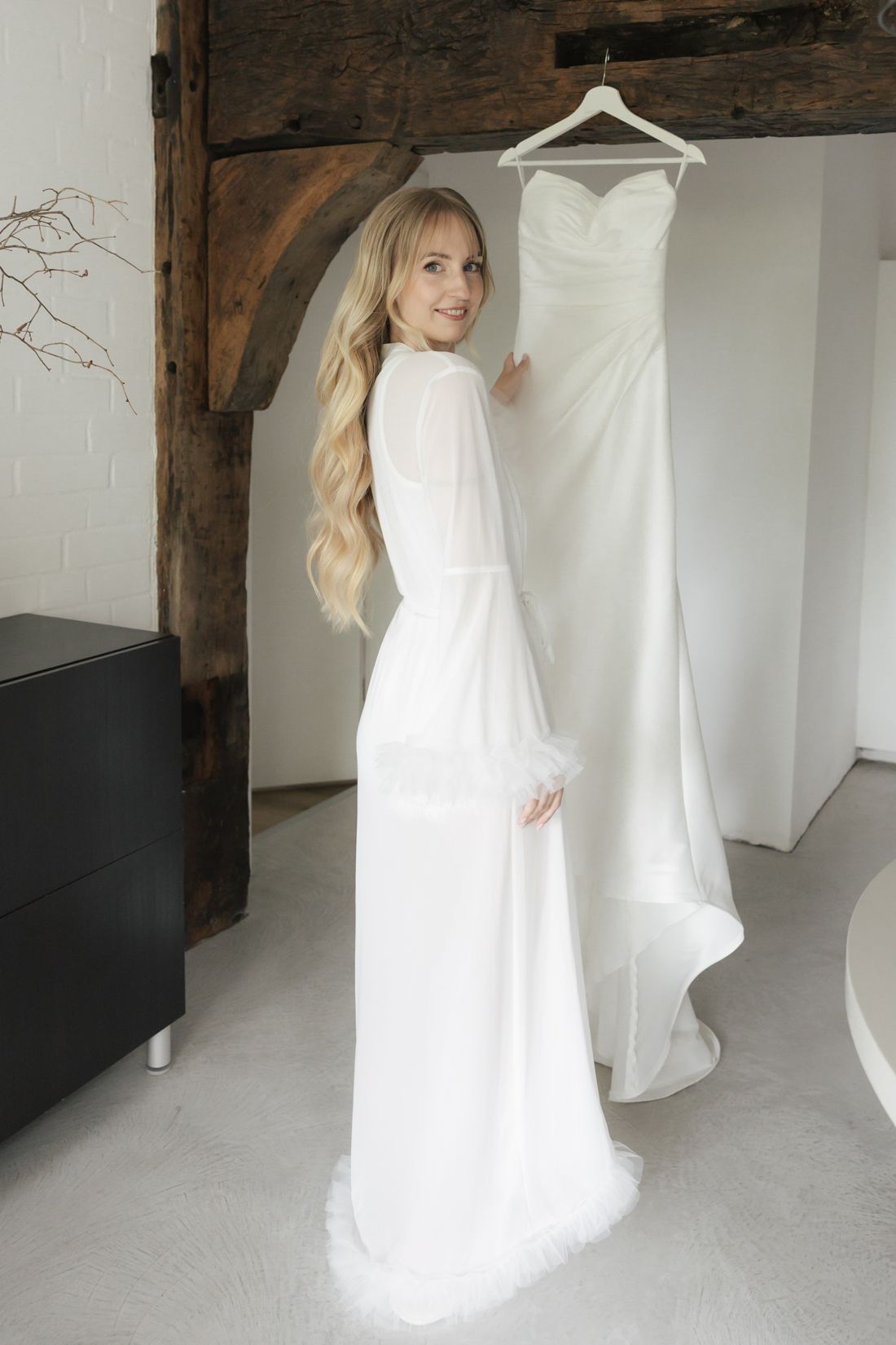 Braut neben ihrem Brautkleid am Morgen